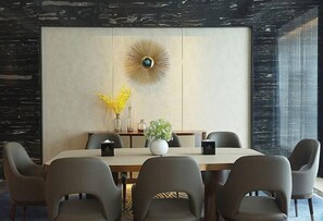 A modern dining area with a large table, six chairs, a decorative wall piece, and a vase with yellow flowers. - Hengxu International Hotel (Yibin)