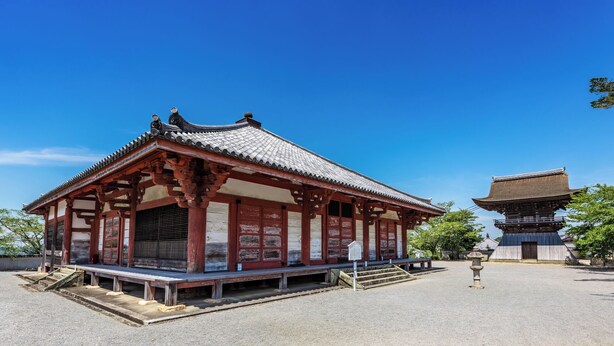 Ein traditionelles japanisches Gebäude mit einem Ziegeldach, Holzbalken und einem Steinsockel.
