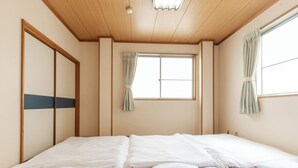 Ein Zimmer mit einem großen Bett, Holzbalkendecke und einem fenster mit Vorhängen.