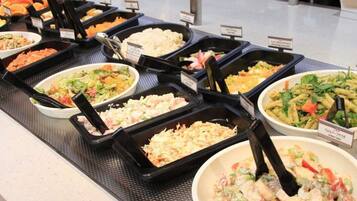 A buffet with various dishes including salads, pasta, and rice.