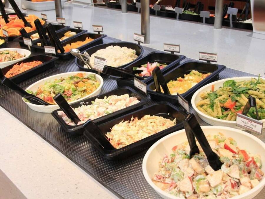 A buffet with various dishes including salads, pasta, and rice.