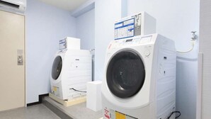 Uma lavanderia com duas máquinas de lavar empilhadas, um painel de controle e um aquecedor de água.