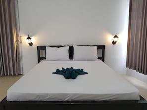 A hotel room with a large bed, two bedside lamps, and a window with curtains.