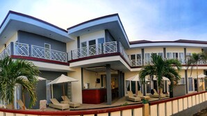 A modern hotel with a curved facade, multiple balconies, and outdoor seating areas. - Talent Resort (Gili Trawangan)