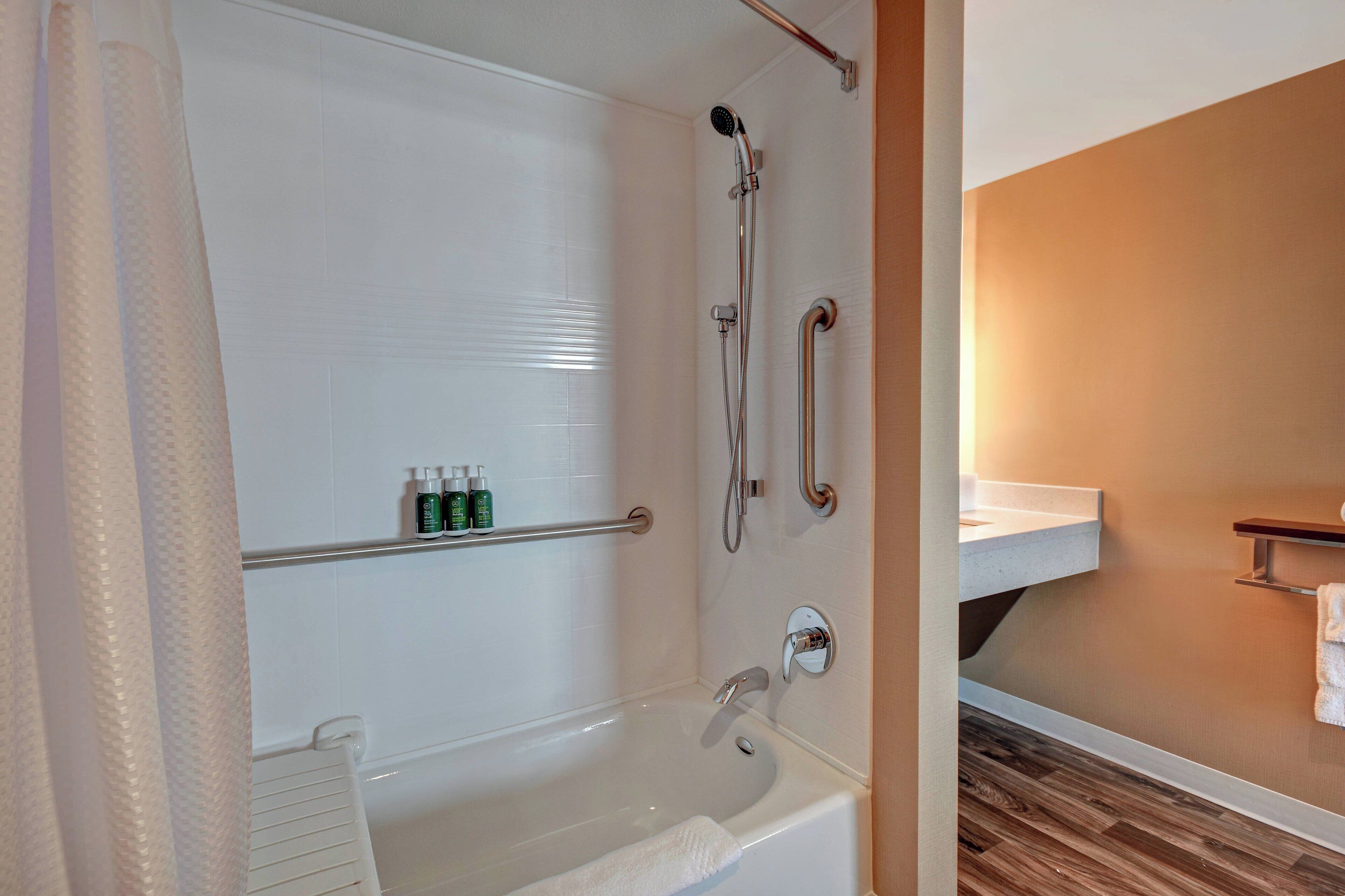 Une salle de bain moderne équipée d’une baignoire, d’une douche et d’un meuble-lavabo avec un porte-serviettes.