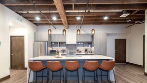 A modern kitchen with a central island, bar stools, and pendant lighting. - Historic Downtown Loft  with King Bed and Wifi (Spokane)