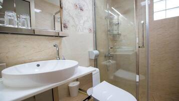 Un baño moderno con un lavamanos grande y blanco, inodoro y cabina de ducha con paredes de vidrio.