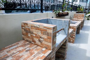 Outdoor seating with stone-patterned tables and benches, a metal fence, and potted plants. - Residence Lodge (Saipan)