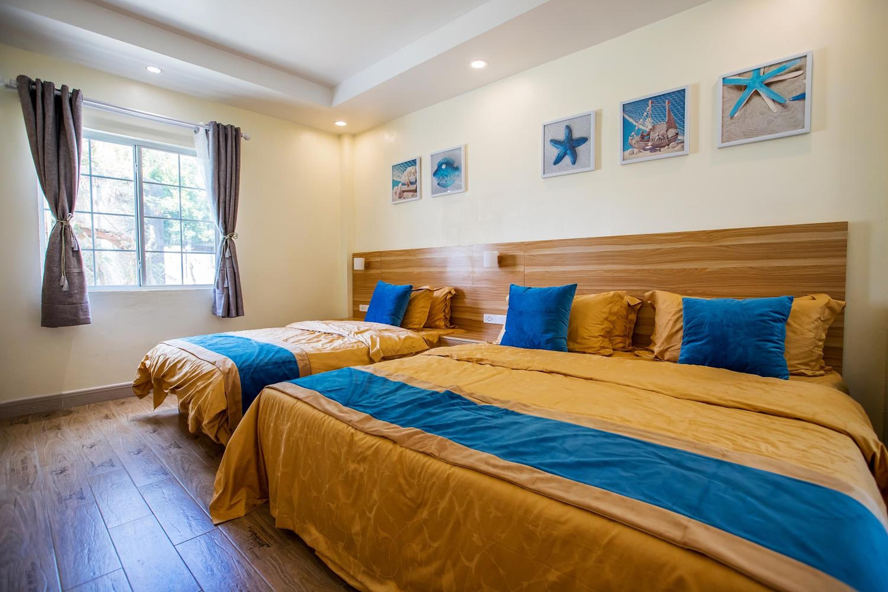 A hotel room with two beds, wooden headboards, and artwork on the wall.