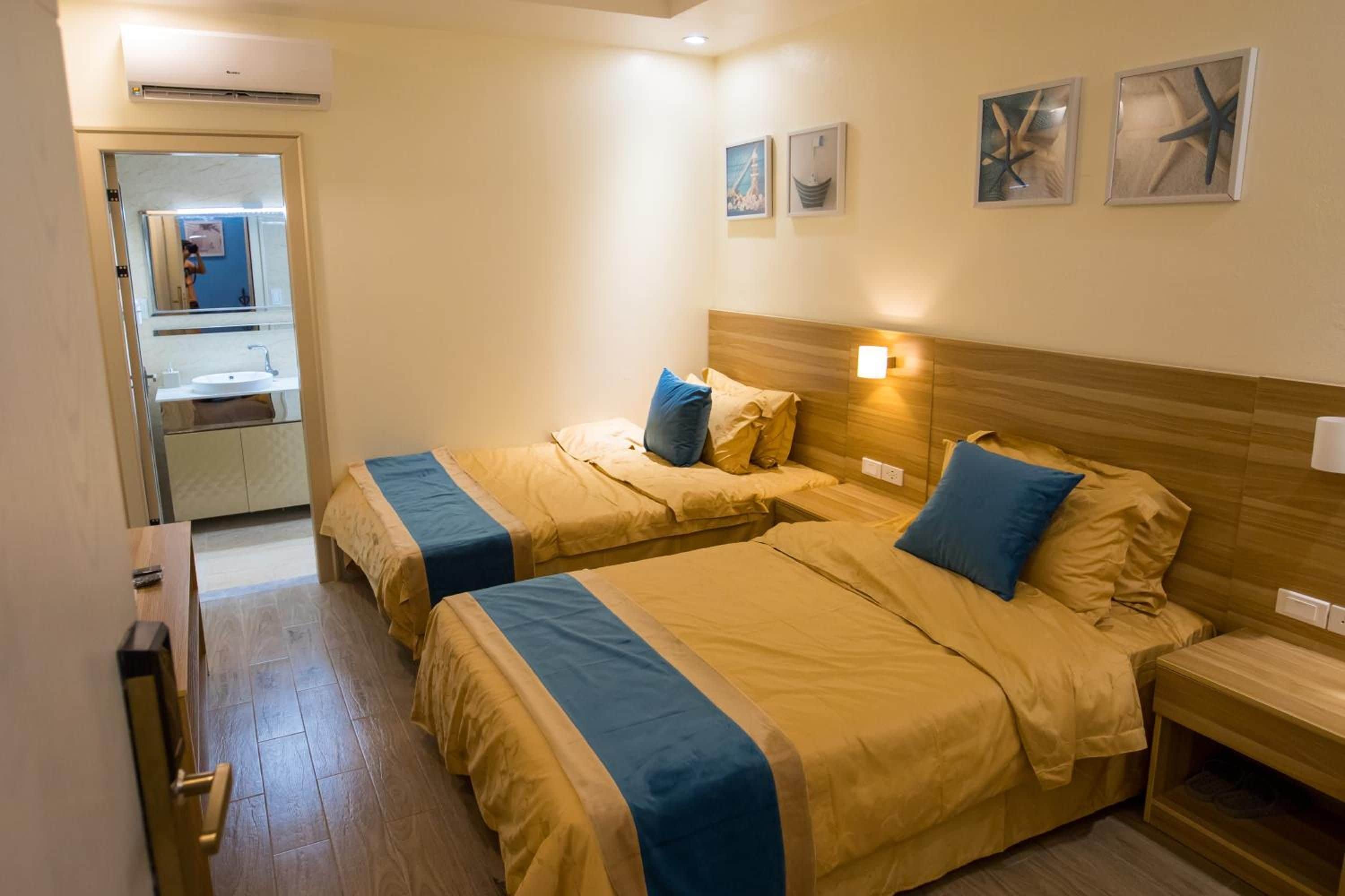 A hotel room with two beds, a bathroom, and a mirror.