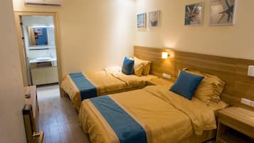 A hotel room with two beds, a bathroom, and a mirror.