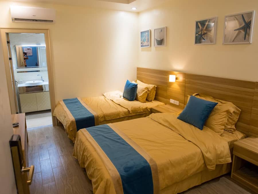 A hotel room with two beds, a bathroom, and a mirror.