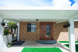 A building entrance with a brick facade, a wooden door, and a small window. - Residence Lodge (Saipan)