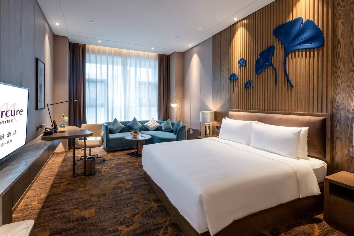 Une chambre d’hôtel avec un lit, un canapé, un bureau et une télévision.