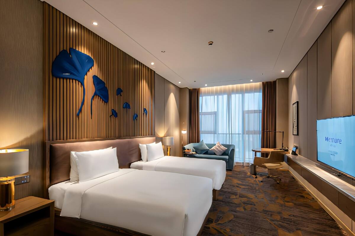 Une chambre d’hôtel avec deux lits, un canapé, une télévision et une grande fenêtre.