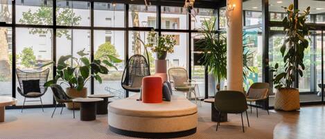 A modern interior with a central seating area, large windows, and indoor plants.