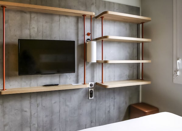 A modern room with a mounted TV, wooden shelves, and a small table.