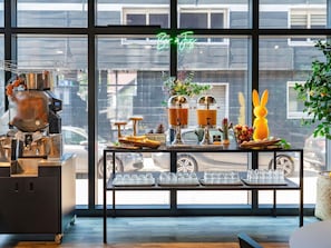 Interior de una cafetería con una máquina de café, una vitrina con vasos y un letrero de neón que dice 'Bar a Jus'.