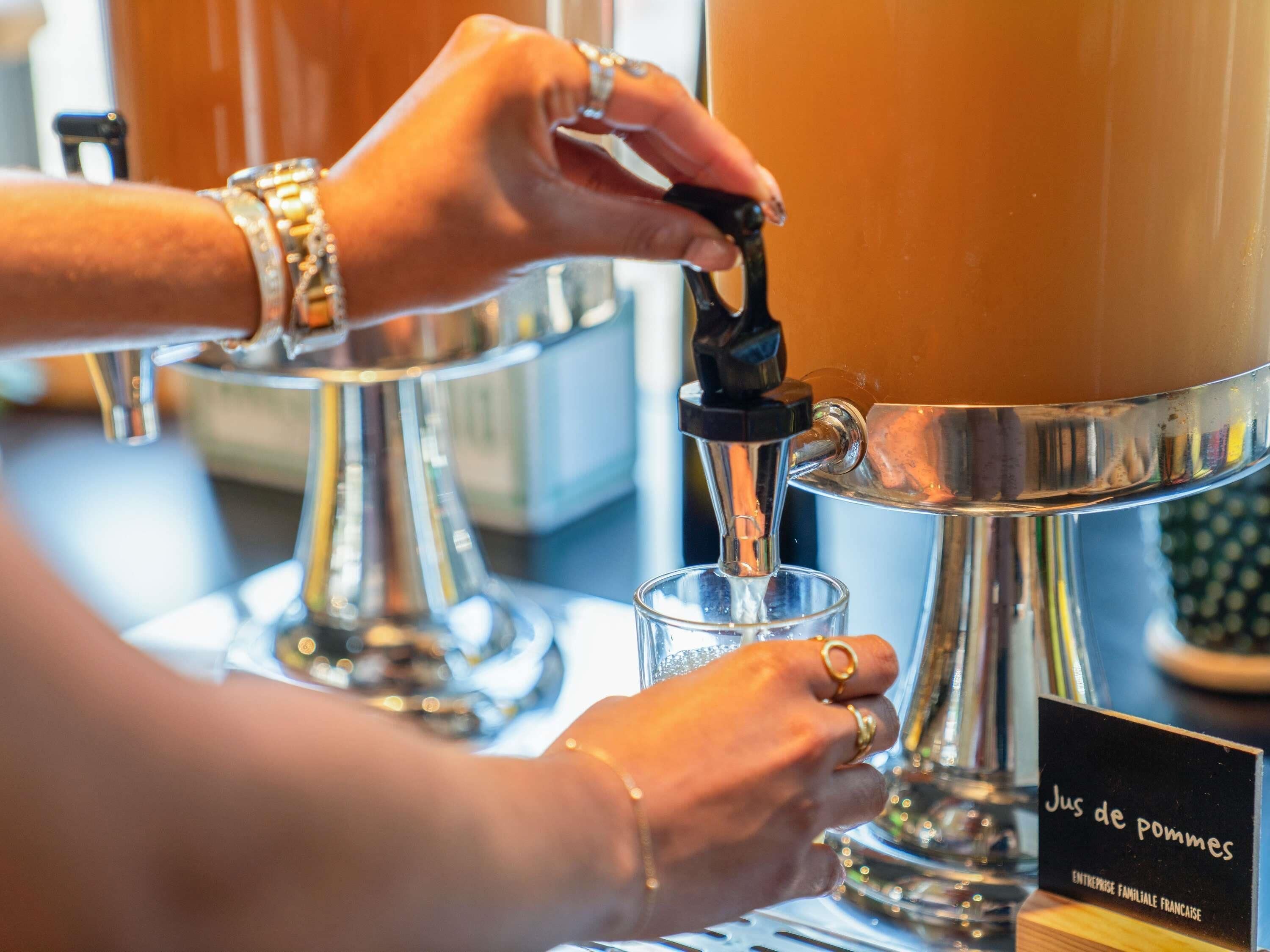 A person pouring a beverage from a tap into a glass.