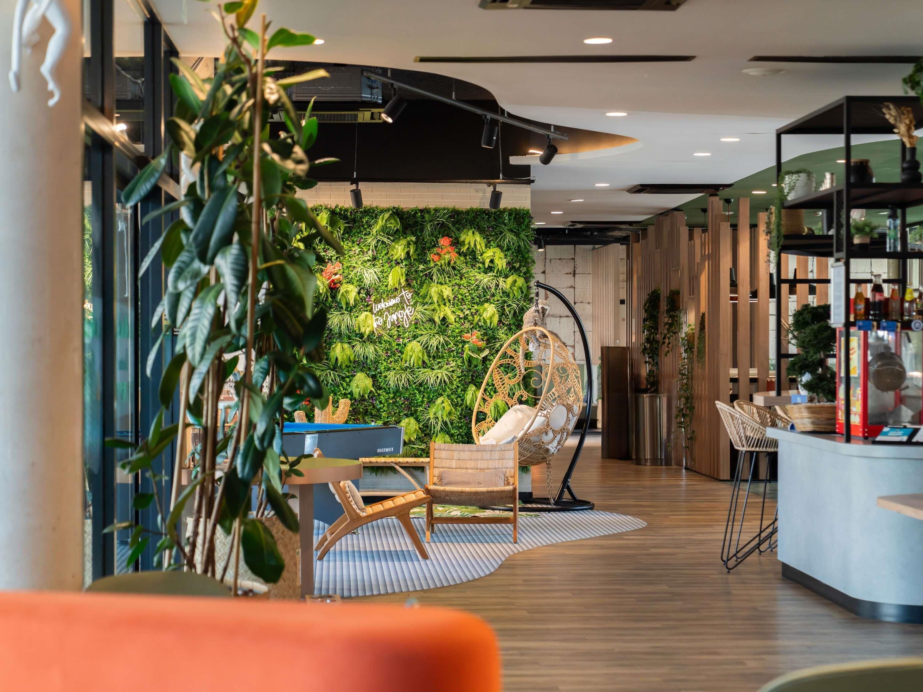 Un interior moderno con una pared verde, una silla colgante y una zona de bar.