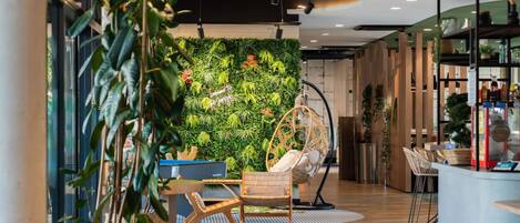 A modern interior with a green wall, a hanging chair, and a bar area.