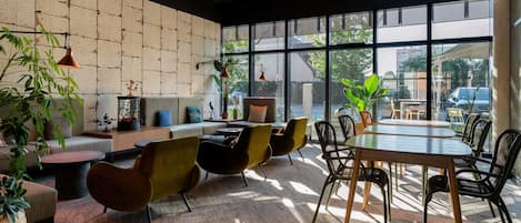Un intérieur moderne avec un mur en briques, de grandes fenêtres et différents types d’agencements de sièges.