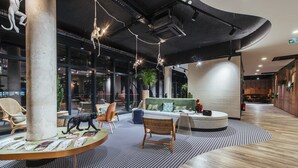 A modern lounge area with a round table displaying magazines, a sofa, and a chair. - ibis budget Rouen Centre Rive Gauche (Rouen)