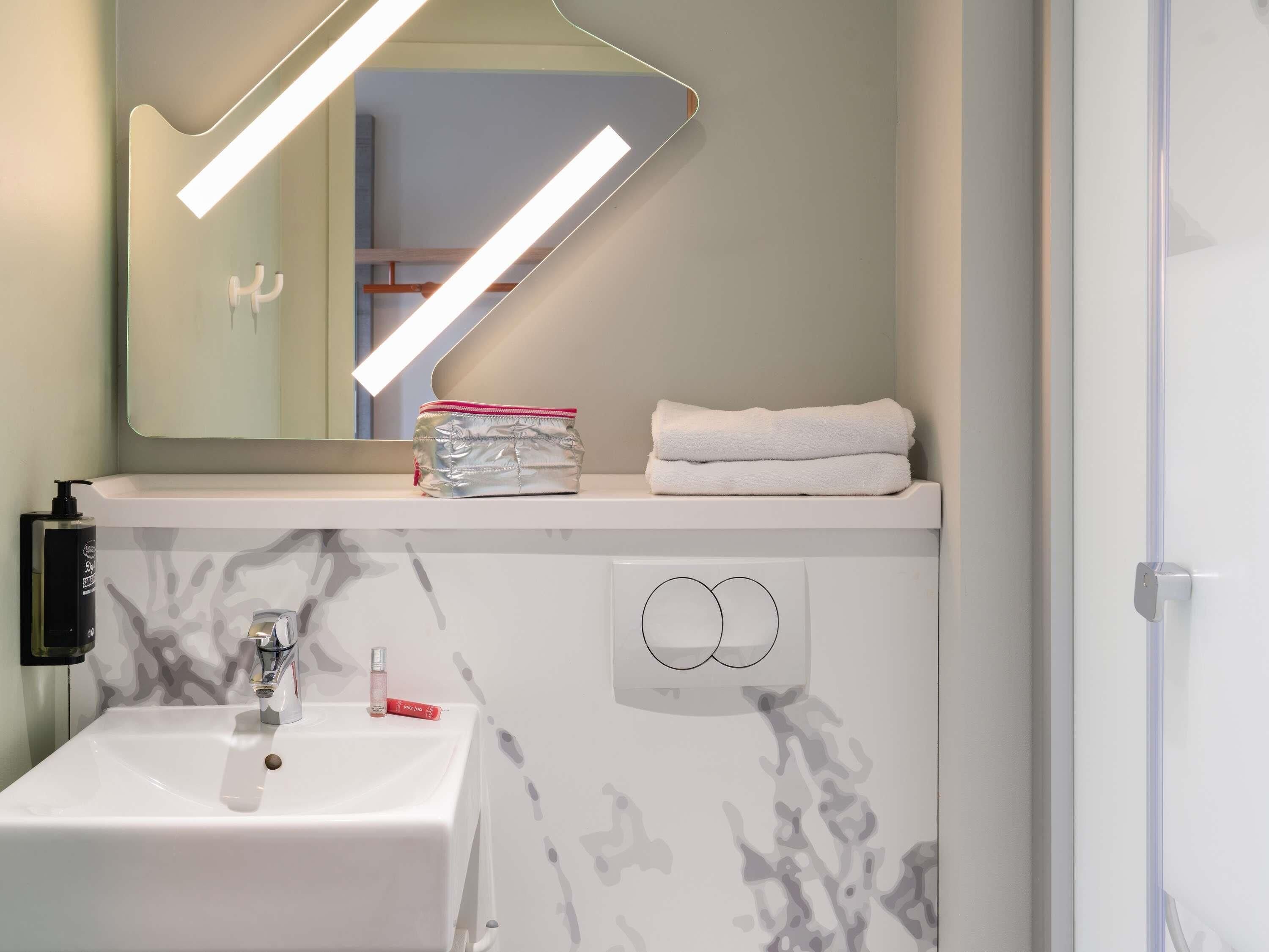 A bathroom with a white sink, a mirror, a towel, and a bottle of lotion.