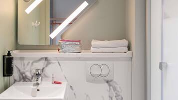 A bathroom with a white sink, a mirror, a towel, and a bottle of lotion.