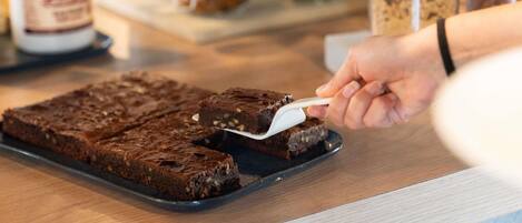 A person cutting a brownie on a tray.