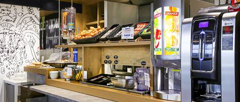 Un comptoir de café avec une machine à café, des pâtisseries et un tableau affichant le menu.