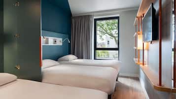 Une chambre d’hôtel avec deux lits, un téléviseur fixé au mur et une fenêtre donnant sur des immeubles.