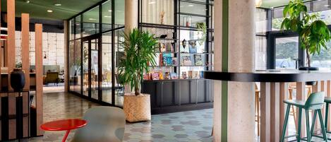 A modern interior with a hexagonal tiled floor, a central seating area with red and grey chairs, and a bookshelf with books and decorative items.
