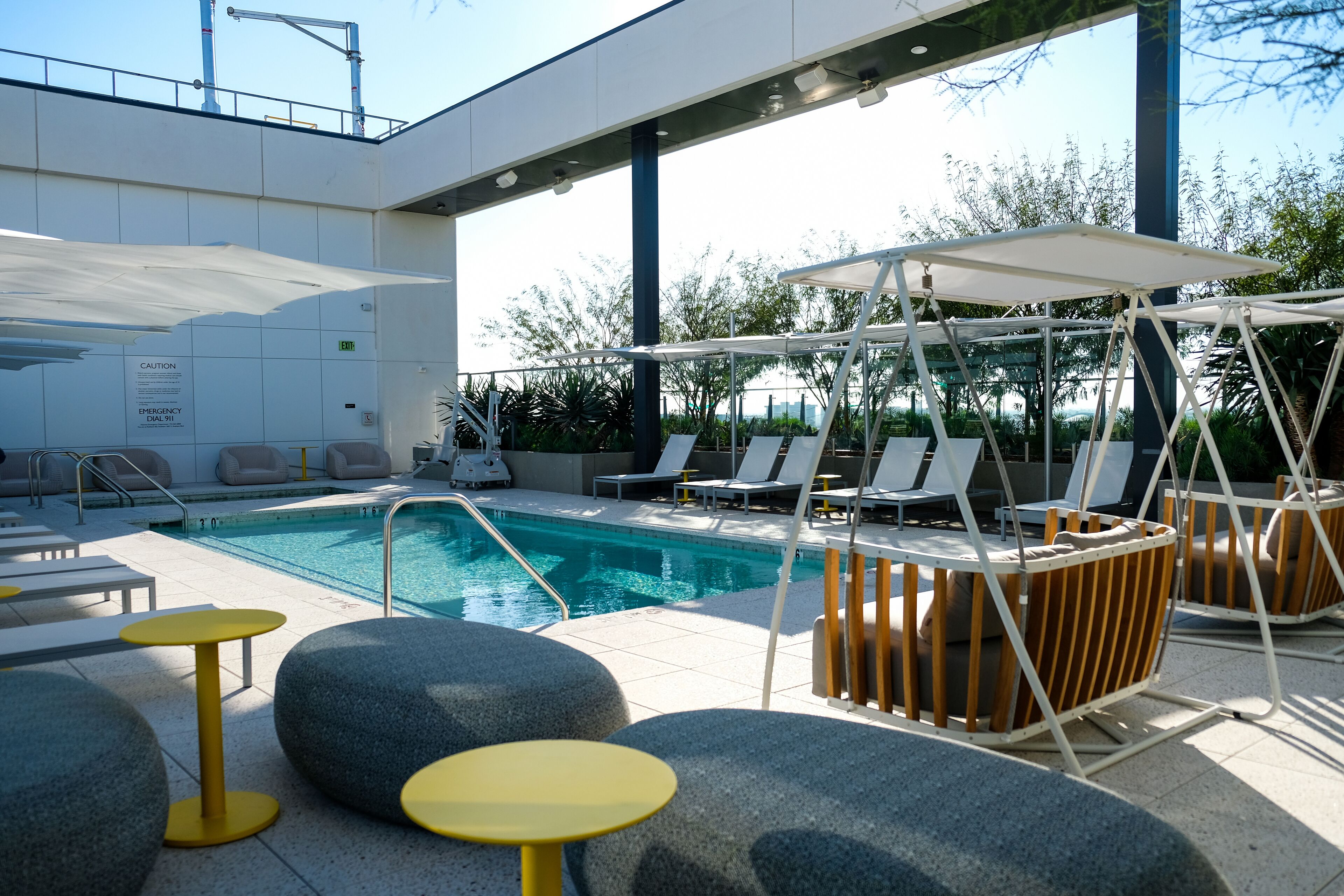 A poolside area with lounge chairs, a pool, and a covered seating area.