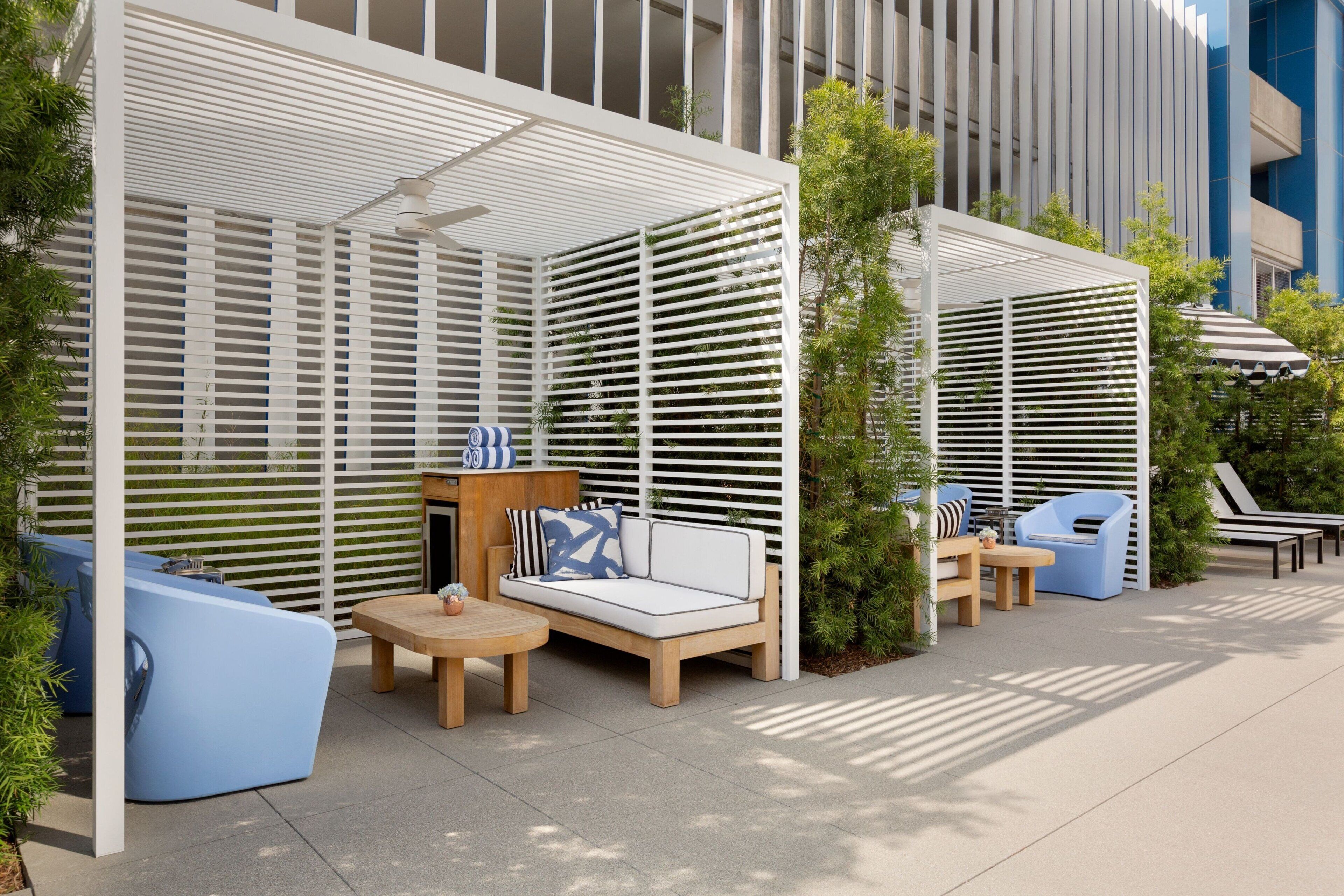 An outdoor seating area with a sofa, chairs, and a table, surrounded by a white lattice structure.