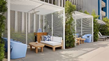An outdoor seating area with a sofa, chairs, and a table, surrounded by a white lattice structure.