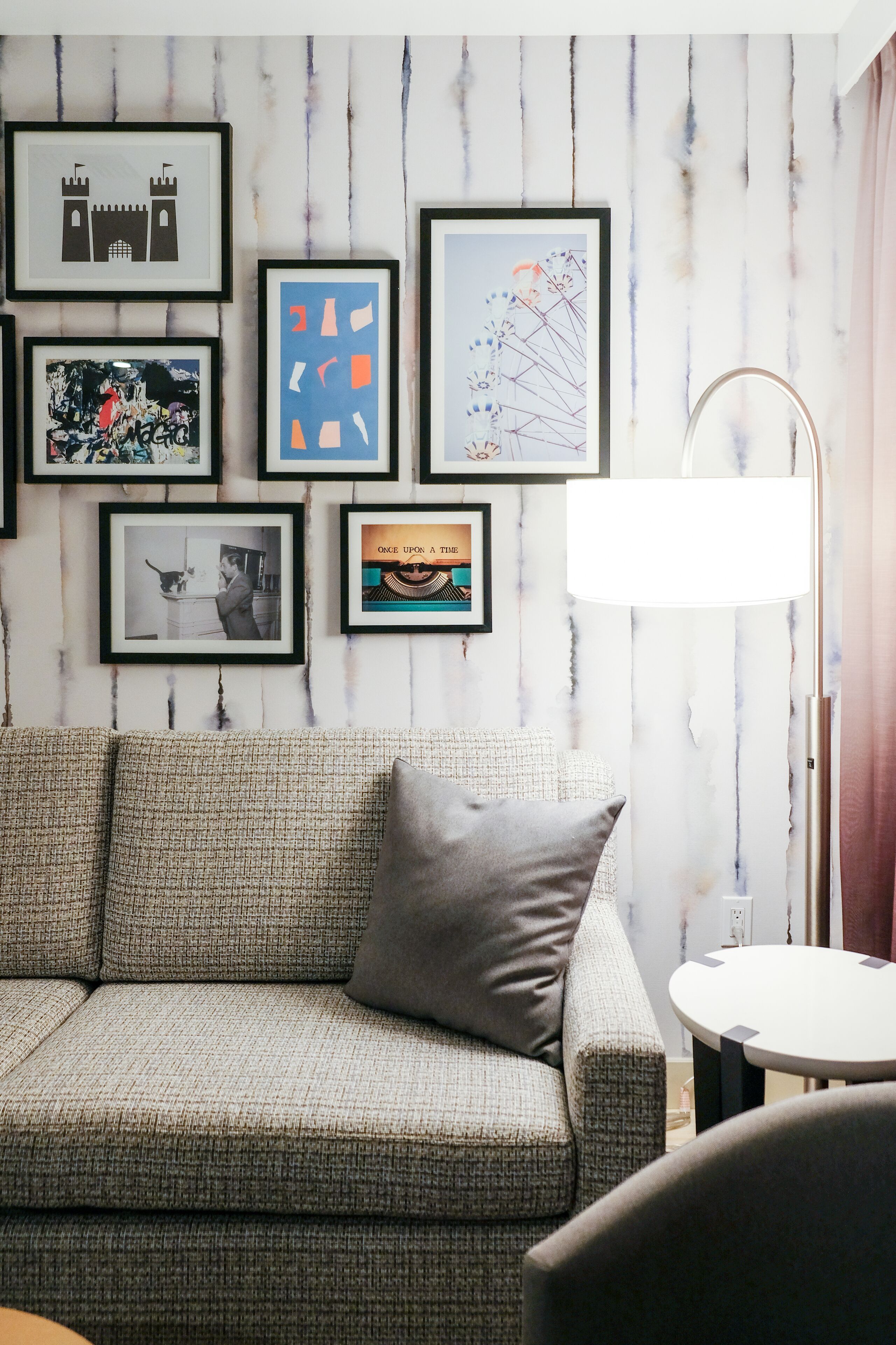 A living room with a sofa, framed artwork, and a floor lamp.