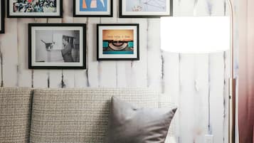 A living room with a sofa, framed artwork, and a floor lamp.
