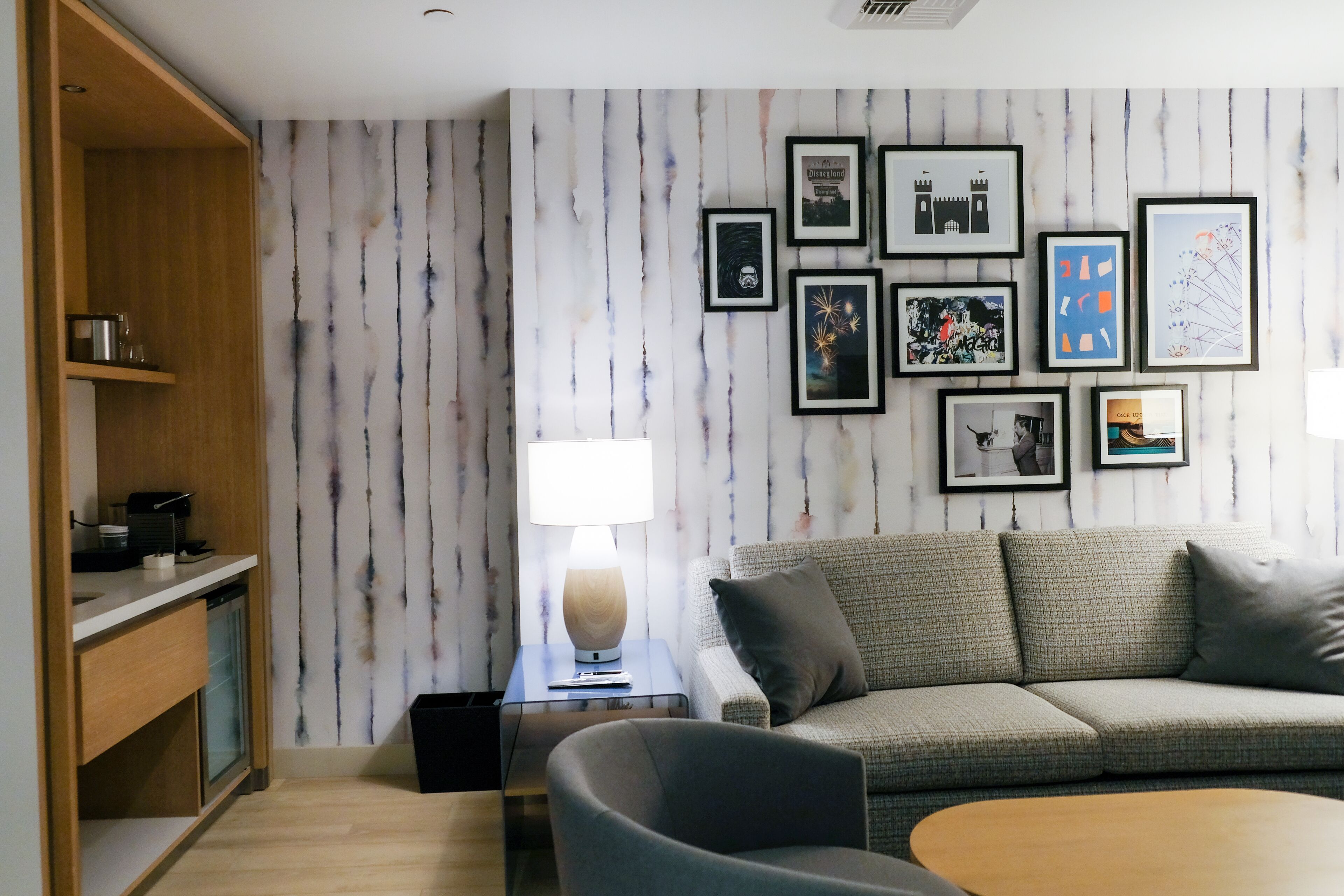 A modern living room with a grey sofa, a wooden coffee table, and a wall with framed pictures.