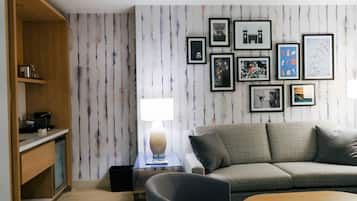 A modern living room with a grey sofa, a wooden coffee table, and a wall with framed pictures.