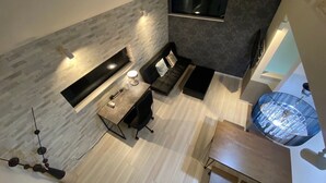 A modern loft-style living space with a high ceiling, a built-in fireplace, a seating area with a sofa and a coffee table, and a dining table with chairs. - Shibuya Stay Tokyo (Tokyo)