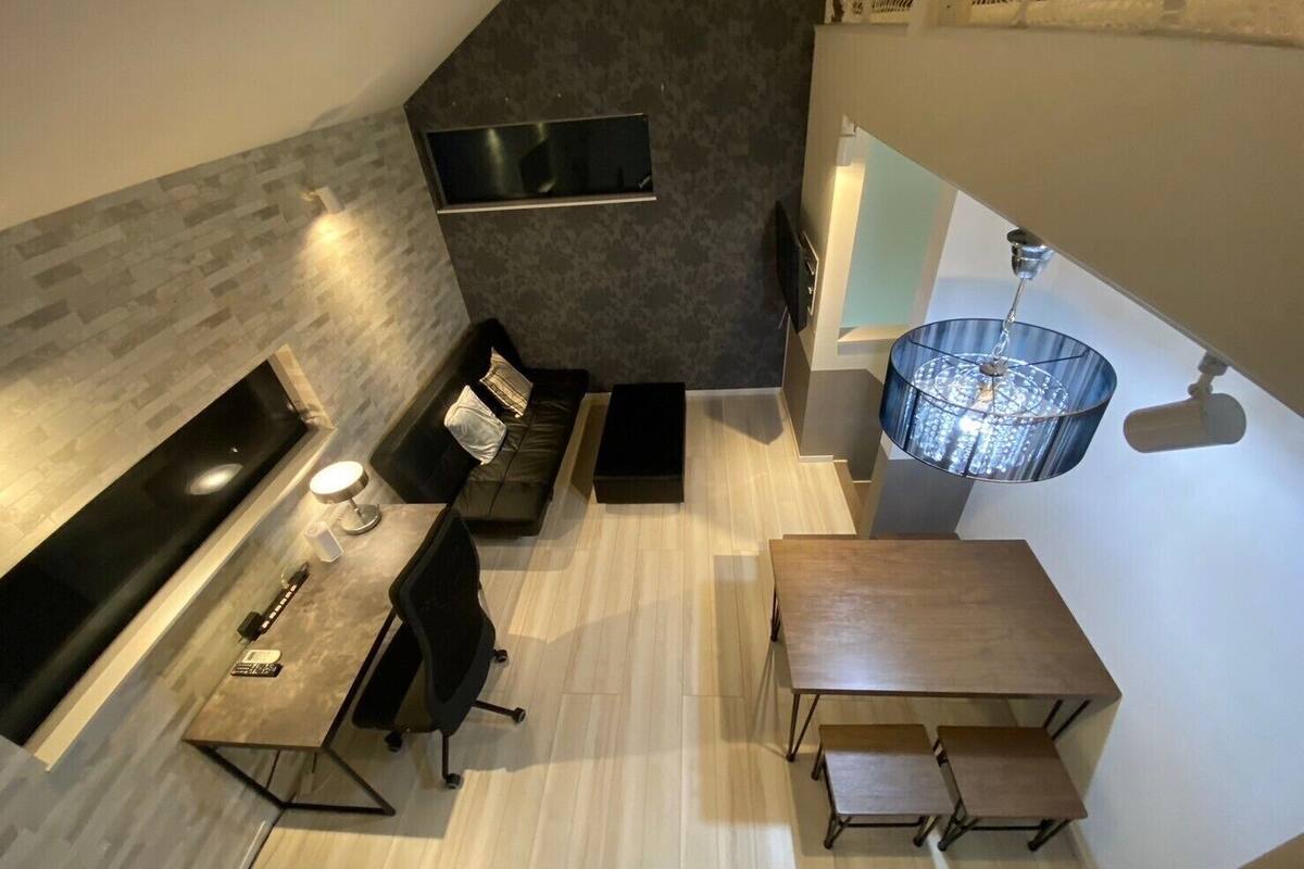 Un espacio habitable moderno estilo loft, con cocina, una mesa de comedor y una zona de estar con sofá y sillas.