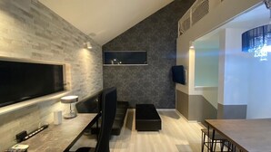 A modern living room with a large flat-screen TV, a dining table, and a seating area with a sofa and chairs. - Shibuya Stay Tokyo (Tokyo)