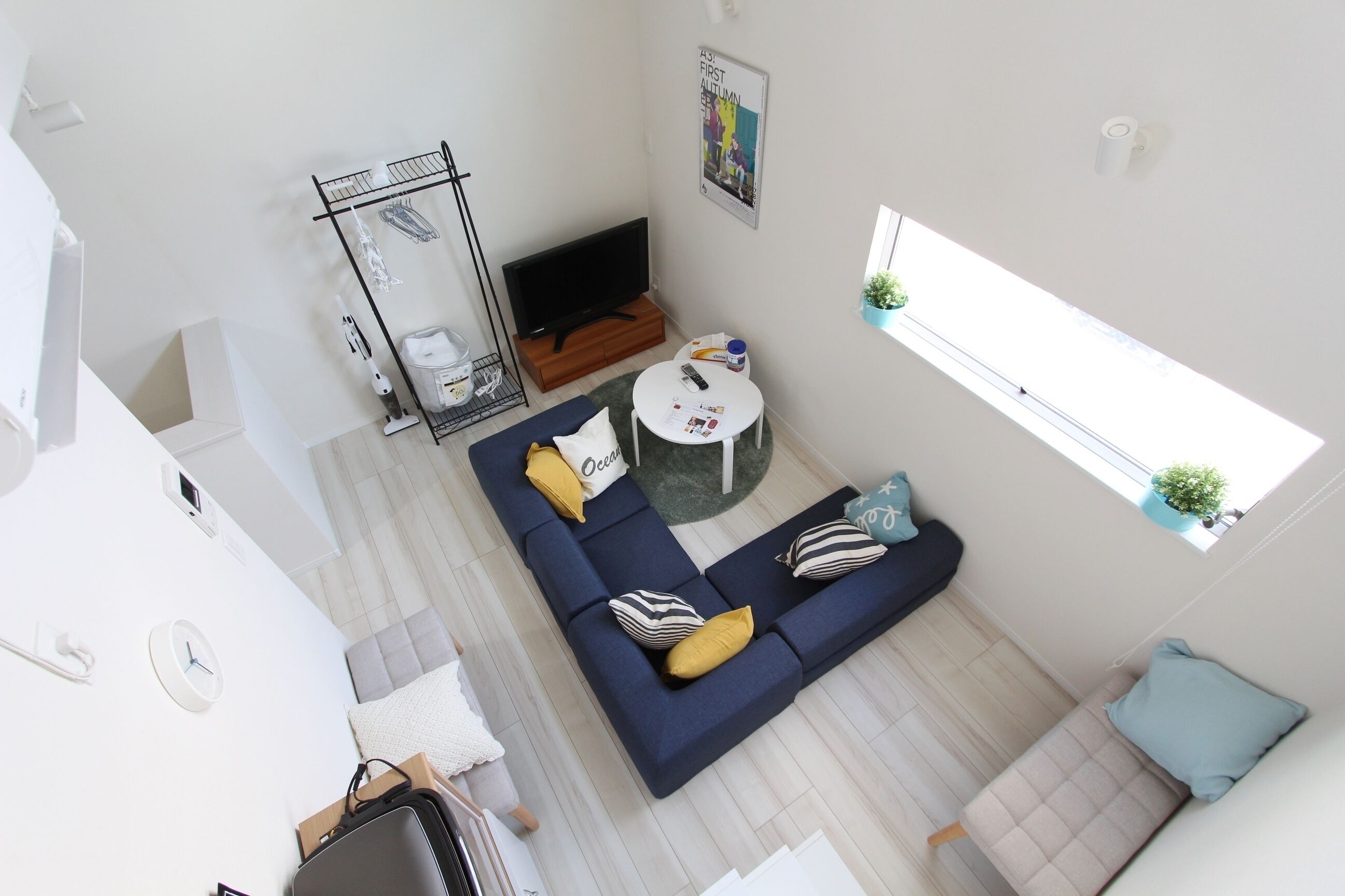 A modern living room with a blue sofa, a small round table, a TV, and a window with a plant.