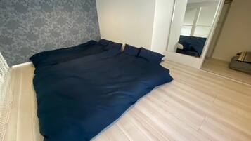Quarto com cama grande, piso de madeira, parede cinza com padrão e um espelho.