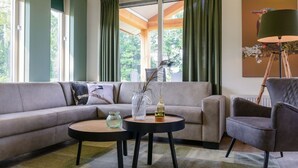 A modern living room with a sectional sofa, two round coffee tables, a side table, and a floor lamp. - Terraced Home in Voorthuizen Near Veluwe (Voorthuizen)