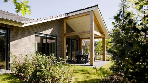 A modern house with a covered patio, brick exterior, and a garden area. - Terraced Home in Voorthuizen Near Veluwe (Voorthuizen)