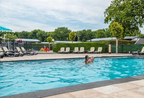 A swimming pool with lounge chairs and a fenced area. - Gorgeous Chalet With Dishwasher in Noordwijk, Near the Sea (Noordwijk)