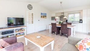A modern living room with a flat-screen TV, a wooden coffee table, and two sofas. - Gorgeous Chalet With Dishwasher in Noordwijk, Near the Sea (Noordwijk)