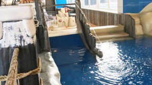 An indoor water feature with a castle-like structure, a rope barrier, and a wooden boat-like element. - Gorgeous Chalet With Dishwasher in Noordwijk, Near the Sea (Noordwijk)